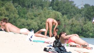 Nude beach girl sunbathes next to her man outdoors